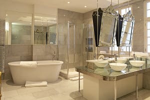 Spacious, tiled bathroom with twin washbasins on a centre island, a freestanding