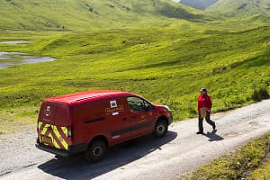 A post women delivering the mail to the remote Strathan at the head of Loch Arkaig, Highlands, Scotland, UK.