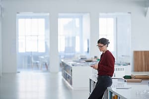 Woman working in open plan office using mobile phone