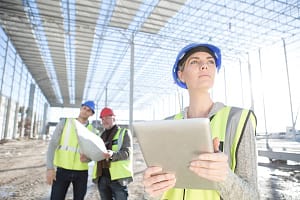 Female surveyor looking up from digital tablet on construction site