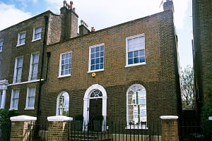 Exterior view of a Georgian-style, three story, townhouse with fenced terrace.