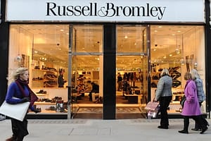Pedestrians walk by Russel and Bromley i..........