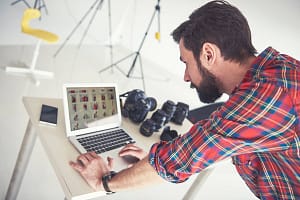 Male photographer  reviewing photo shoot on laptop in studio