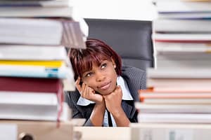 portrait of black businesswoman sitting behind piles of paper