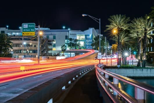Light trails from evening traffic on a palm-lined road in Miami Beach