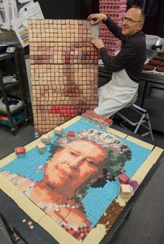 Chef Gerhard Jenne works on a test section of a pixellated portrait of Queen Elizabeth II, made out of cakes, at Konditor and Cook, in the City of London.
