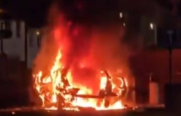 The New IRA hijack a car and blow it up outside a police station in Belfast