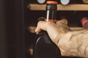 Bavaria, Germany – 11 may 2021: man takes a bottle of red wine from a wine refrigerator.