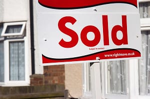 Estate agent sign outside a suburban property.