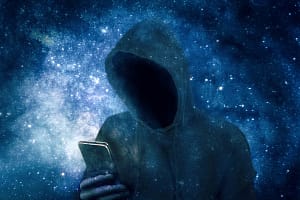 Cyber criminal in hoodie with smartphone