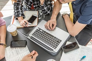 Cropped shot of business team using laptop at cafe meeting