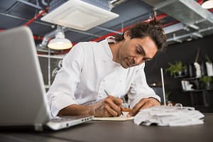 Chef in restaurant writing in notepad