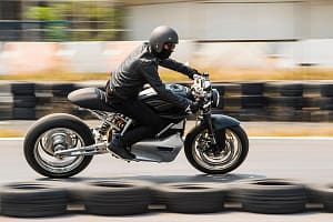 Man testing electric cafe racer motorbike on race track