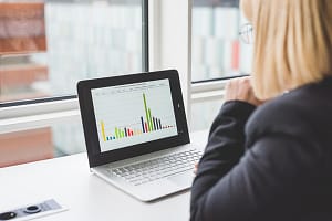 Over shoulder view of businesswoman looking at bar graph on office  laptop