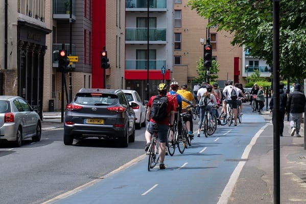 Cyclists on the Cycle Superhighway CS3, Cable Street at a busy intersection – East London, 17th May 2020