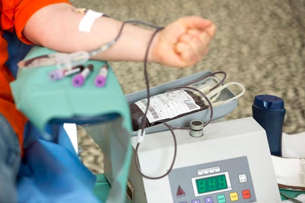 Blood donation hand. Blood bag The hand of a woman who donates blood. Female donor gives blood in a mobile blood donatio