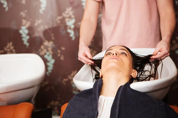 Female customer having hair washed in salon sink