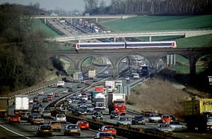 A Chiltern Trains DMU glides gracefully over the congested traffic on the M25 motorway. C1993.