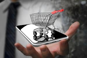 Businessman hand showing shopping cart with smart phone