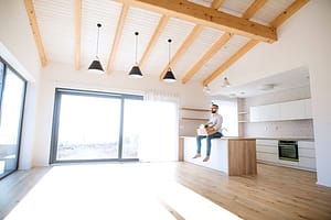 Mature man sitting in unfurnished house, holding a moving box. A mature man sitting in unfurnished house, holding a box.