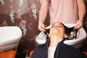 Female customer having hair washed in salon sink