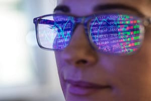 Female expert in glasses looking at screen with financial data