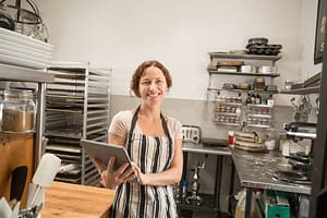 Portrait of female shop assistant with digital tablet in kitchen at country store