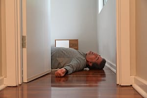 Mature adult man lying on bedroom floor unconscious