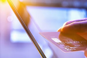 Man using his credit card online for shopping and banking with sunlight coming t