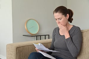 Shocked adult woman reading a letter in home living room