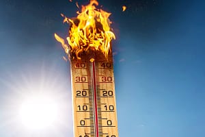Bavaria, Germany – 9 June 2023: burning wooden thermometer in front of a summer sky. Heat wave and heat warning concept