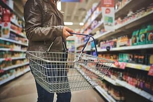 Popping in for a few top ups. a woman holding a basket while shopping at a grocery store. Popping in for a few top ups.