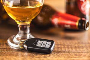 Car key with beer glass on wooden table. Booze driving concept. Drunk driver concept. Car key with beer glass on a woode