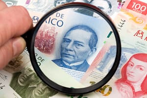 New Mexican Pesos in a magnifying glass a business background New Mexican Pesos in a magnifying glass a business backgro