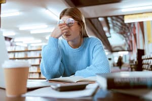 Woman student, fatigue with headache and university burnout, stress for paper deadline or study for exam in library. Cam