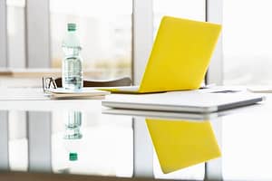 Yellow laptop and bottled water in boardroom
