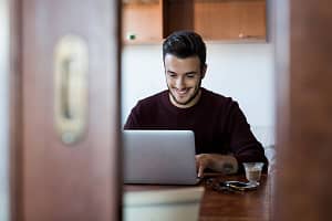 Young man sitting at table using laptop