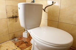 A plumber is repairing an old broken toilet
